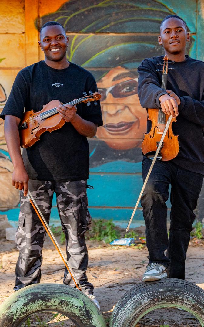 Ayabonga Tshemese, Onke Mbopha, Masi Violin Outreach stand in front of a mural of Nelson Mandela
