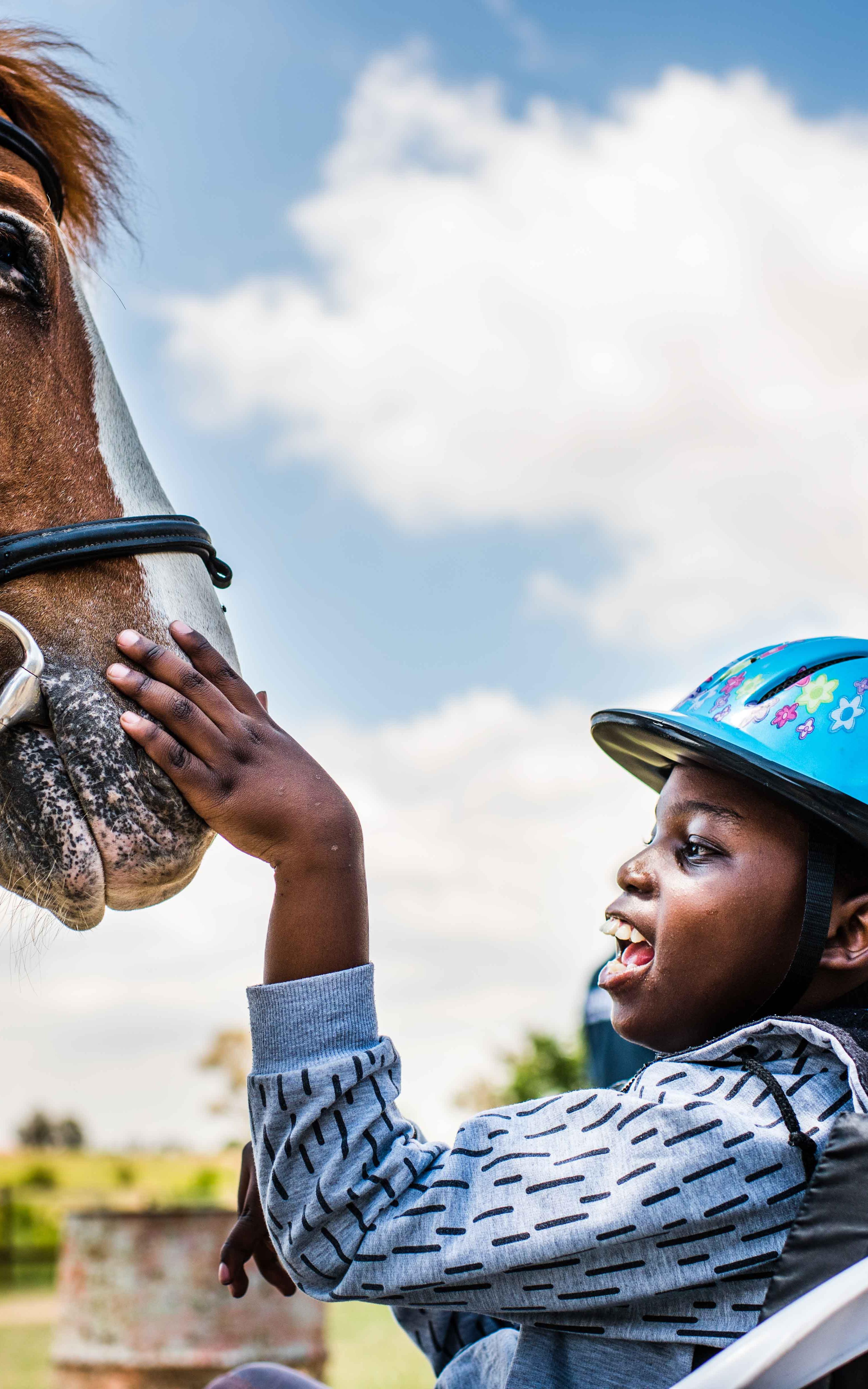 Differently abled boy caressing horse