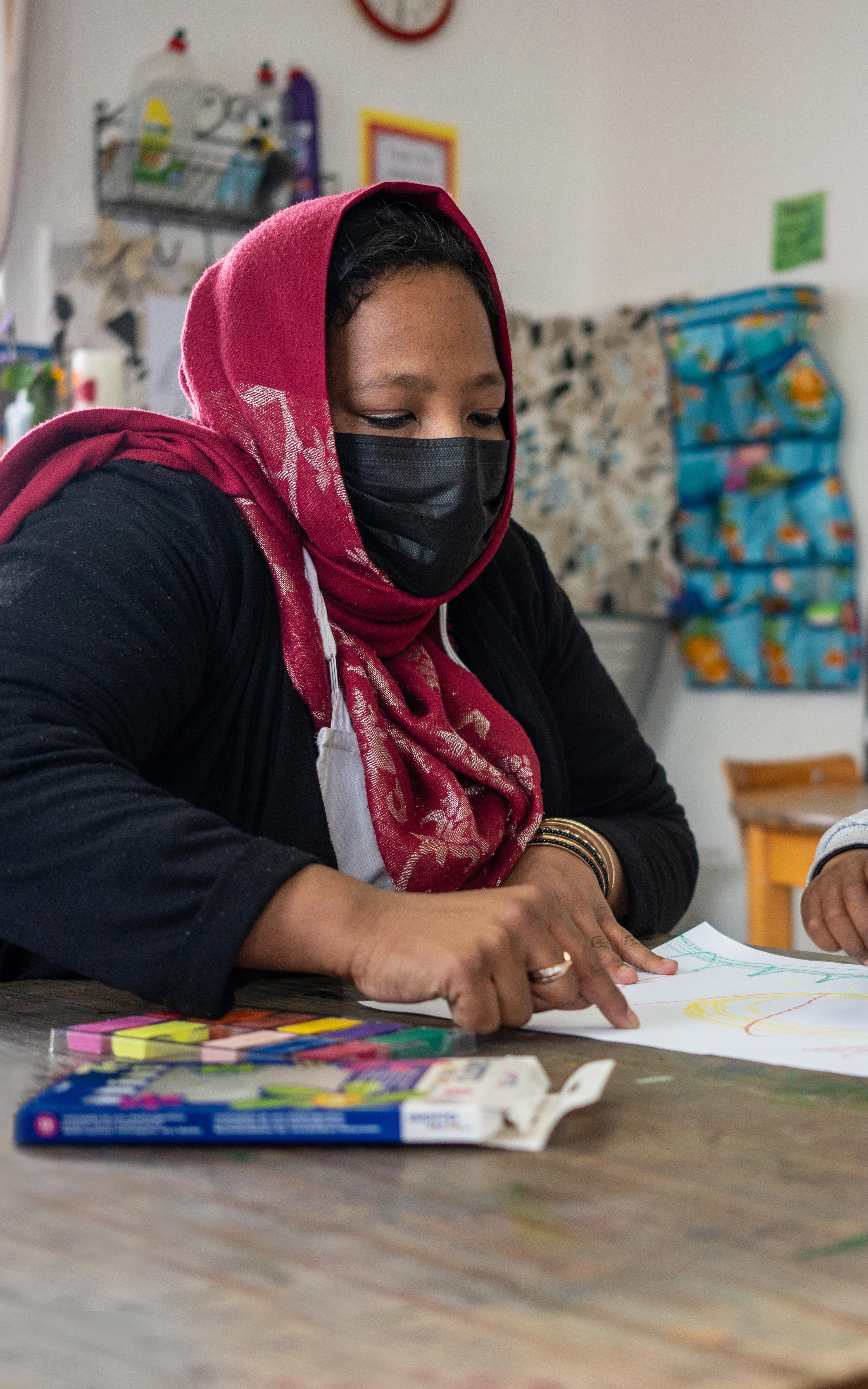 Beautiful News-Masked woman and child looking at drawing