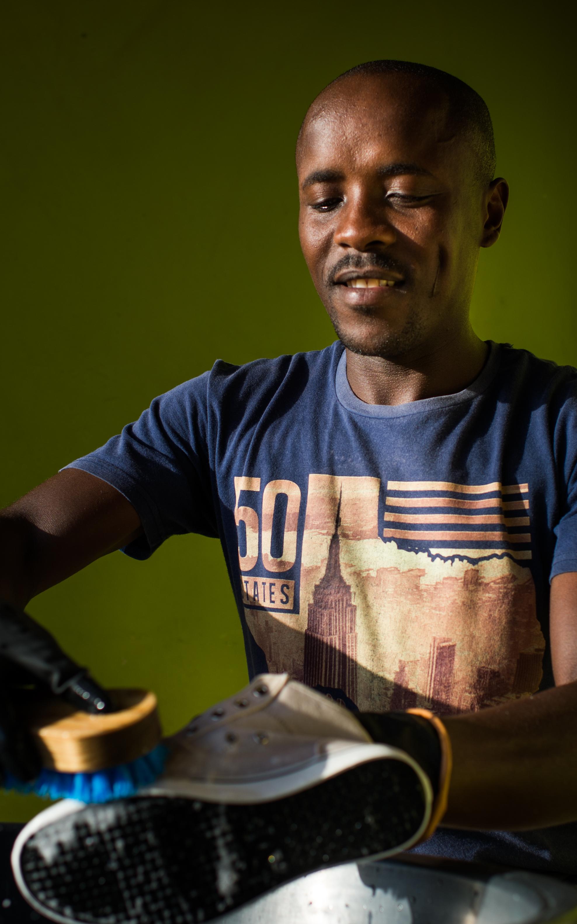 Black man washing a shoe.