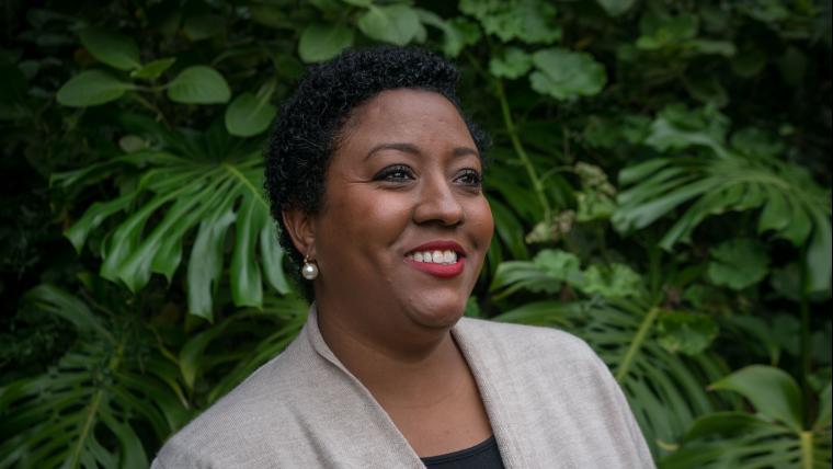 Woman smiling and looking off into the distance in front of trees